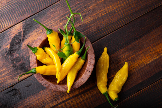 Spicy Organic red yellow chili peppers in a bowl, wooden background, lemon drop pepper copy space for text
