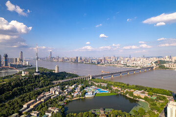 Wuhan city China landscape shows river bridge and tall buildings under blue sky.
