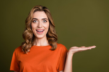 Cheerful woman in orange shirt gesturing with enthusiasm on khaki background