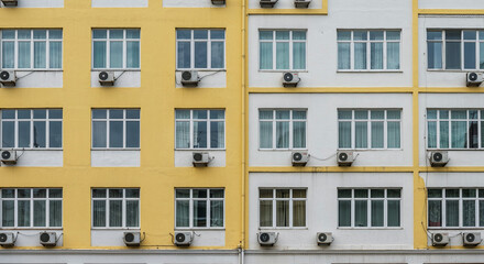 Obraz premium Yellow and white building facade with windows and air conditioners