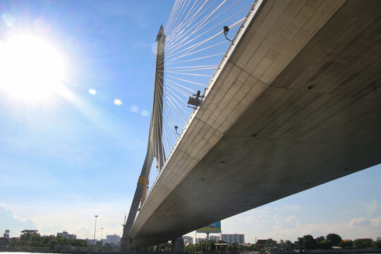 Rama VIII Bridge in Bangkok - A modern cable-stayed bridge over the Chao Phraya River with a bright sky and sun flare. - Powered by Adobe