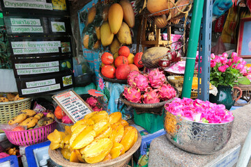 Vibrant Thai market fruit stand - A colorful display of fresh tropical fruits like starfruit, dragon fruit, and mango at a local market stall in Thailand.