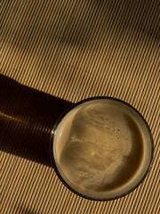 Glass of morning coffee on bamboo wood table with sun light and shadow