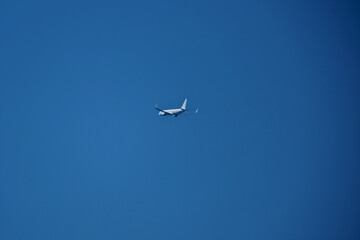 Airplane in the blue sky. A white plane flying in a cloudless blue sky.
