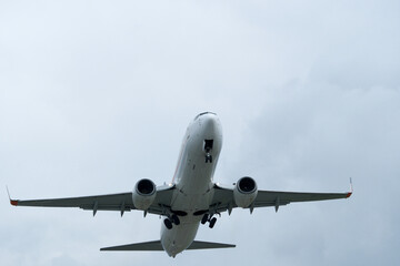 An airplane flies through clouds, observed from the runway.