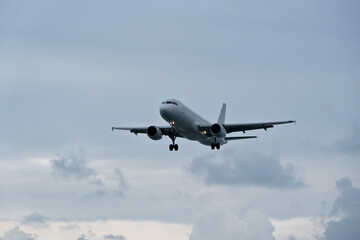 An airplane flies through clouds, observed from the runway.