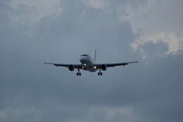 An airplane flies through clouds, observed from the runway.