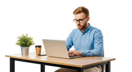 Focused young man in glasses and a blue shirt working on a laptop at a wooden desk with a plant and coffee, isolated on white, showcasing modern work