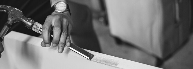 Panorama view side view Asian craftsman with leather watchband carefully carves recess into...