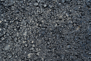 Close-up texture of fresh asphalt road surface with visible aggregate and dark bitumen—abstract industrial background for construction and infrastructure themes