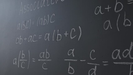 Close-up tilt-down shot of black chalkboard with mathematical equations in classroom - Powered by Adobe