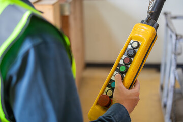 Industrial worker operating control switch panel for machine in factory environment with safety vest and focused hand pressing button