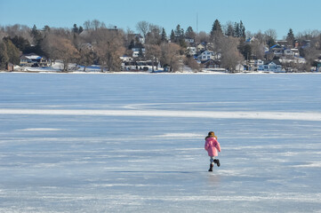 Little girl running in frozen lake in winter 