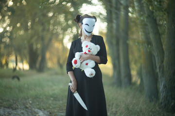 Spooky Halloween scene with mask, teddy bear, and knife