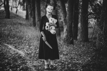 Spooky Halloween scene with mask, teddy bear, and knife