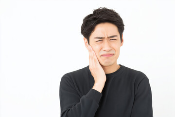 歯の痛みを訴えて頬を押さえる若い男性