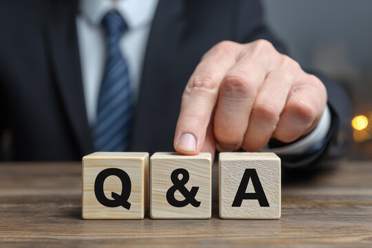 木製の積み木で「Q&A」の文字を並べるビジネスマンの手