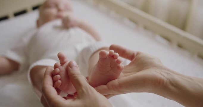 Baby feet in mother hands. Tiny Newborn Baby's feet on female Heart Shaped hands closeup. Happy Family concept. Baby foots close-up. Mother enjoying motherhood checks baby health. Feet heart shape.