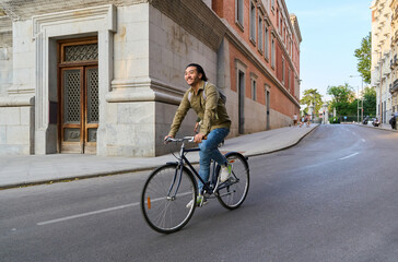 Fototapeta premium Happy student riding bicycle in european city street