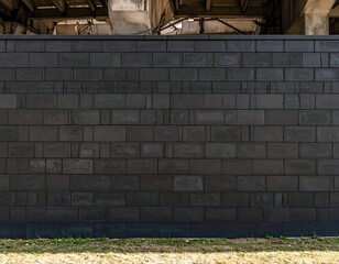 Dark gray rectangular block wall extends to the horizon beneath a bridge
