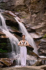 woman performing slow tai chi movements near a waterfall and river at sunset capturing harmony balance and fitness in nature