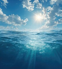 Fototapeta premium Sunlight piercing the ocean surface. Clear blue sky with puffy clouds. Calm ocean waters