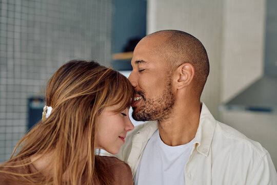 Romantic couple sharing a cozy moment at home, exchanging gentle kisses and expressing deep love and tenderness in their relationship - Powered by Adobe