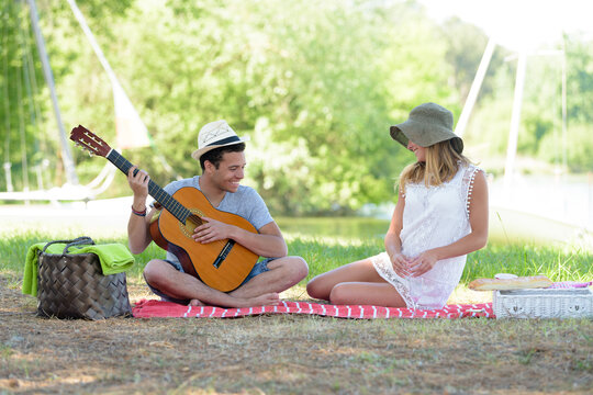 young couple camping playing guitar outdoor