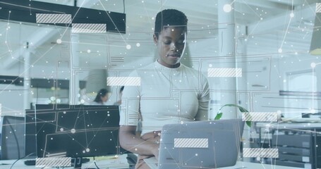 Analyzing IT professional interacting with laptop at modern open plan office, with digital overlays