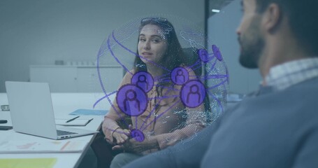 Two coworkers discussing digital network hologram in office meeting room, with laptop and notebook