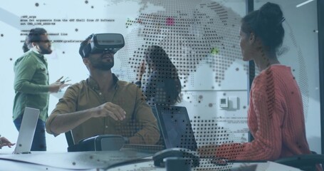 Interacting man wearing VR headset at glass conference table, with laptops phone world-map