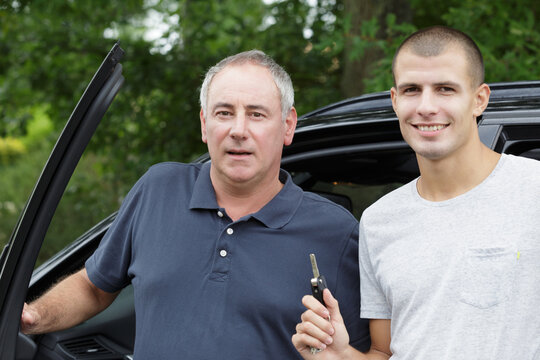 father and son posing next to the car