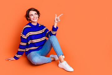 Photo of young brown hair lady in blue striped cute sweater sitting floor directing forefinger...