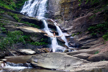 woman performing slow tai chi movements near a waterfall and river at sunset capturing harmony balance and fitness in nature