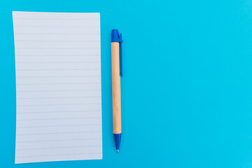 A blank notebook and pencil for writing notes and lists on an empty page with a blue background