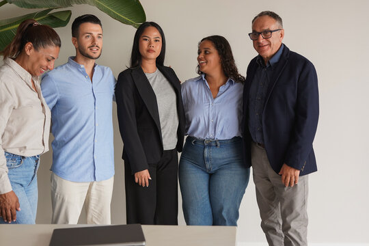 Happy multiracial entrepreneur hugging each other inside modern office - Diverse business people and multi generational colleagues concept
