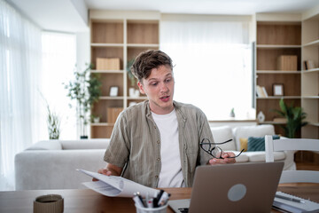 Obraz premium Freelancer working from home having video call on laptop and explaining documents
