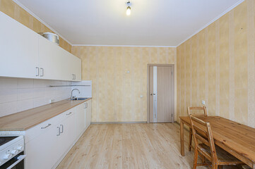 bright kitchen with white cabinets, wood countertop, and a dining table. The walls are covered in striped wallpaper