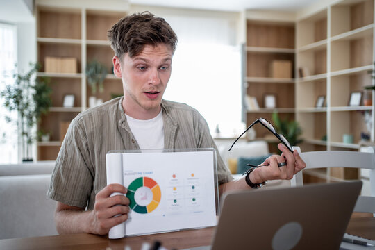 Young businessman showing charts and graphs on a video call from home office