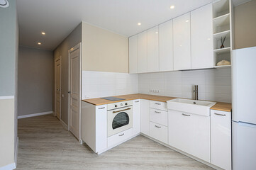 bright kitchen features white cabinets, light wood countertops, and a tile backsplash. Minimalist design with modern appliances