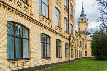 Kyiv. Kyiv Polytechnic Institute. Large, yellow brick building with detailed architectural features, numerous windows, and surrounding green lawns and trees on a cloudy day