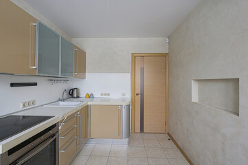 well-lit kitchen with tan cabinets, a light countertop, and beige tile flooring, presenting a clean and functional space