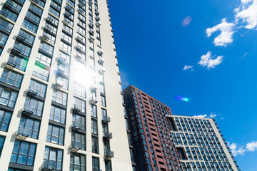 Tall, modern high-rise residential buildings with many windows and balconies on a sunny day with a deep blue sky