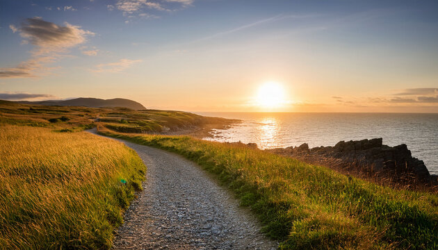 serene coastal walking trail with winding gravel pathway alongside the ocean at sunset surrounded by grassy fields and rocky shoreline peaceful nature scene