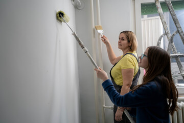 Single mother painting apartment with teen daughter during home renovation, inspiring girl power DIY project, mother and child bonding
