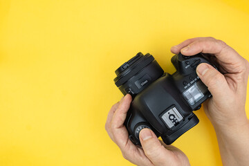 Hands using digital camera on a yellow background with copy space. Top view, minimalism.