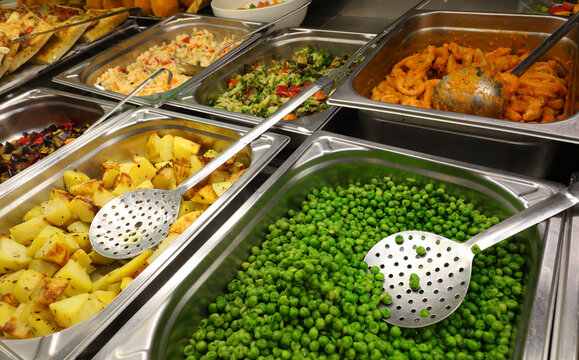 trays of self service canteen with hot dishes and vegetables like potatoes and green peas