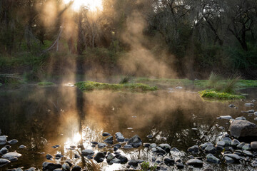 Natural art canvas print of a rocky lake with mist rising above the water's surface toward the warm...