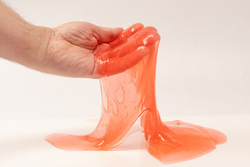 Red slime toy in man hand isolated on white.