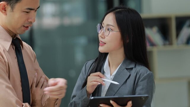 Professional business colleagues reviewing data on tablet, working together strategically in contemporary office environment, sharing collaborative insights